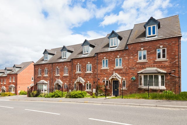 A row of British new-build terraced houses in a residential area.