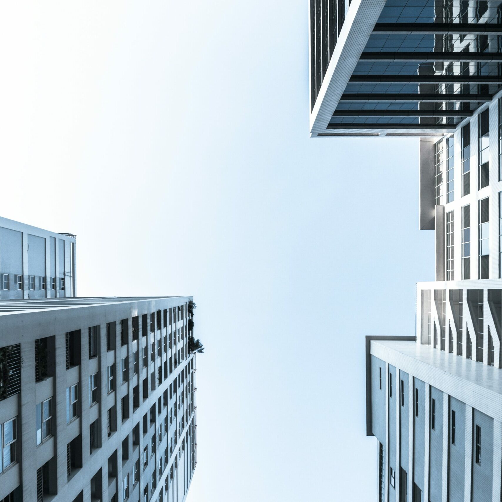 An image of high-rise office buildings and blue sky, taken from the ground pointing upwards.